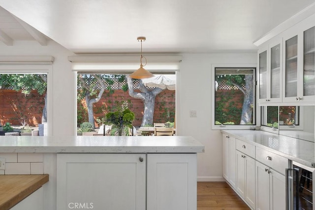 484 E 16th St, Costa Mesa, CA 92627 - kitchen with beverage cooler, white cabinetry, glass insert cabinets, light wood-type flooring, and pendant lighting