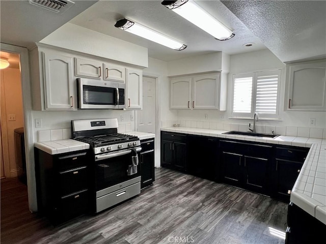 14016 Las Entradas, Bakersfield, CA 93314 - kitchen featuring stainless steel appliances, tile countertops, dark wood-style floors, dark cabinets, and a textured ceiling