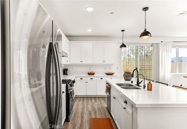872 Bluebell Way, Beaumont, CA 92223 - kitchen featuring freestanding refrigerator, gas stove, a center island with sink, light wood-style floors, and white cabinets