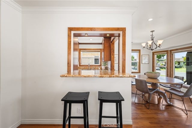 5116 Faust Ave, Lakewood, CA 90713 - kitchen featuring ornamental molding, a chandelier, wood finished floors, a kitchen breakfast bar, and light stone counters