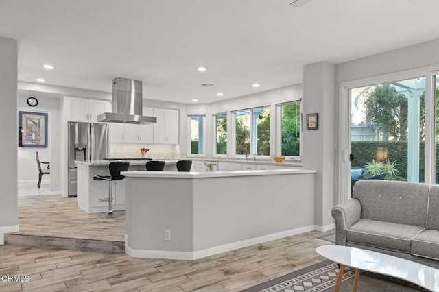 2106 Fox Den Ct, Oxnard, CA 93036 - kitchen with wall chimney range hood, stainless steel fridge with ice dispenser, light wood-style flooring, white cabinetry, and light countertops