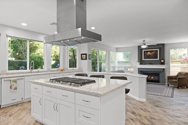 2106 Fox Den Ct, Oxnard, CA 93036 - kitchen with island range hood, dishwasher, stainless steel gas cooktop, a brick fireplace, and open floor plan