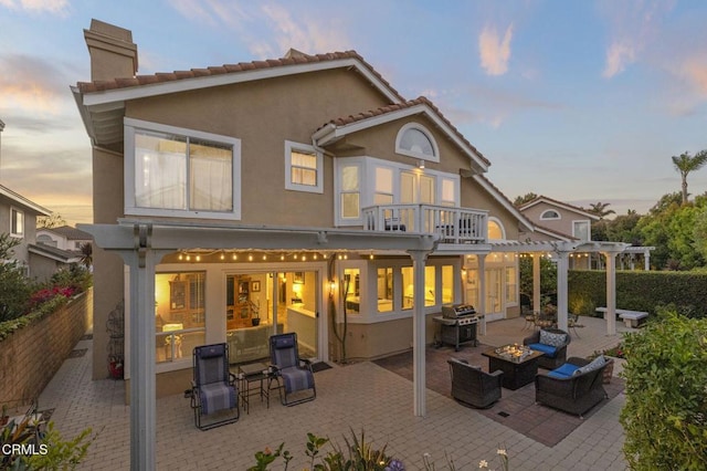 2106 Fox Den Ct, Oxnard, CA 93036 - back of house at dusk featuring a chimney, a patio area, stucco siding, an outdoor living space with a fire pit, and a pergola