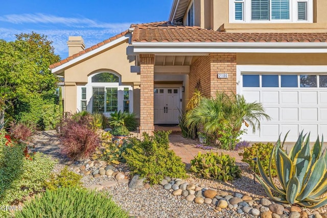 2106 Fox Den Ct, Oxnard, CA 93036 - entrance to property featuring a chimney, brick siding, an attached garage, and stucco siding
