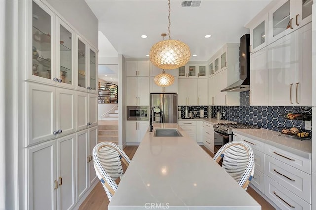 19325 Peachtree Ln, Huntington Beach, CA 92648 - kitchen featuring wall chimney range hood, a kitchen island with sink, stainless steel appliances, white cabinets, and recessed lighting