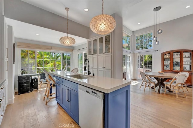 19325 Peachtree Ln, Huntington Beach, CA 92648 - kitchen featuring white dishwasher, blue cabinets, light countertops, light wood-style floors, and a kitchen island with sink