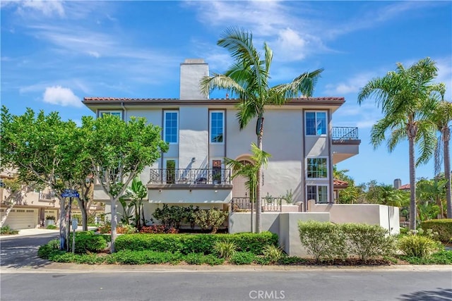 19325 Peachtree Ln, Huntington Beach, CA 92648 - view of front of property featuring a chimney, stucco siding, a balcony, and a tile roof