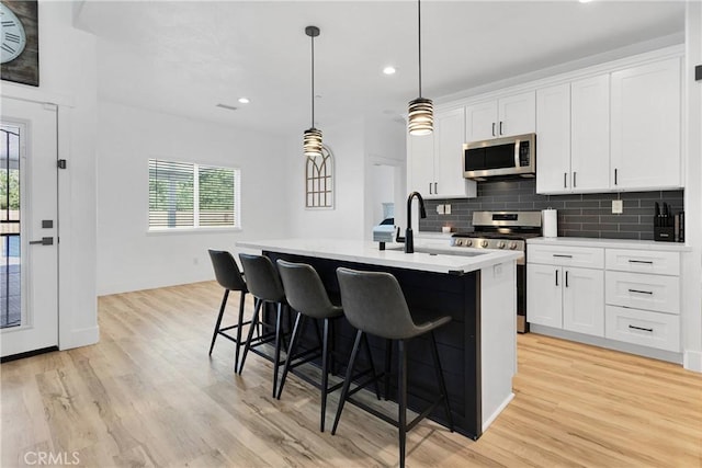 12207 Snapping Turtle Rd, Apple Valley, CA 92308 - kitchen with stainless steel appliances, light wood-style flooring, a center island with sink, decorative backsplash, and recessed lighting