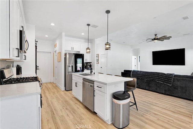12207 Snapping Turtle Rd, Apple Valley, CA 92308 - kitchen featuring stainless steel appliances, a breakfast bar, open floor plan, light wood-style floors, and white cabinets