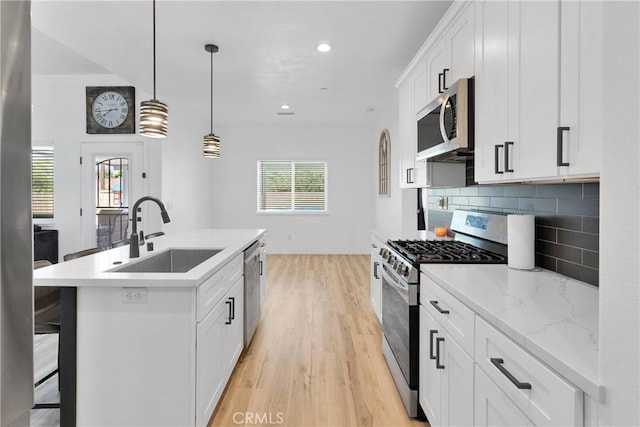 12207 Snapping Turtle Rd, Apple Valley, CA 92308 - kitchen with stainless steel appliances, decorative backsplash, a center island with sink, light wood-type flooring, and white cabinetry