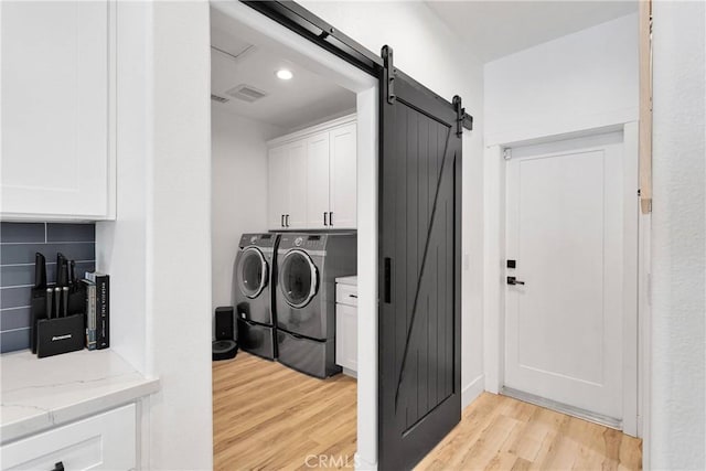 12207 Snapping Turtle Rd, Apple Valley, CA 92308 - washroom with washer and dryer, cabinet space, light wood-type flooring, and a barn door