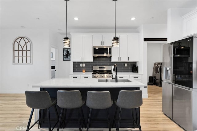12207 Snapping Turtle Rd, Apple Valley, CA 92308 - kitchen with appliances with stainless steel finishes, backsplash, white cabinets, a kitchen breakfast bar, and light wood-type flooring