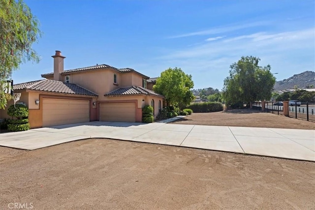 16858 Mariposa Ave, Riverside, CA 92504 - view of property exterior featuring an attached garage, driveway, stucco siding, a tiled roof, and a chimney