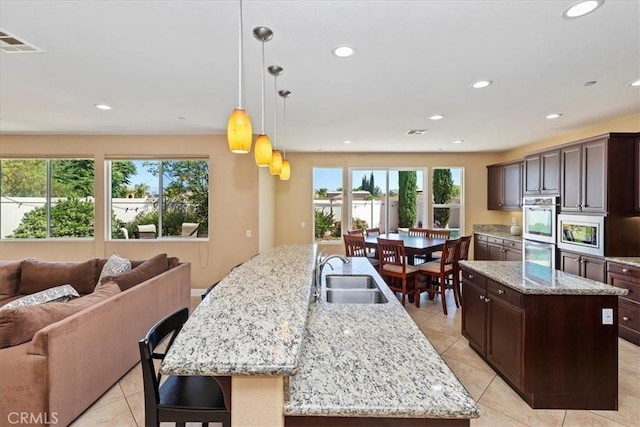 16858 Mariposa Ave, Riverside, CA 92504 - kitchen with a large island with sink, open floor plan, appliances with stainless steel finishes, light tile patterned floors, and dark brown cabinets