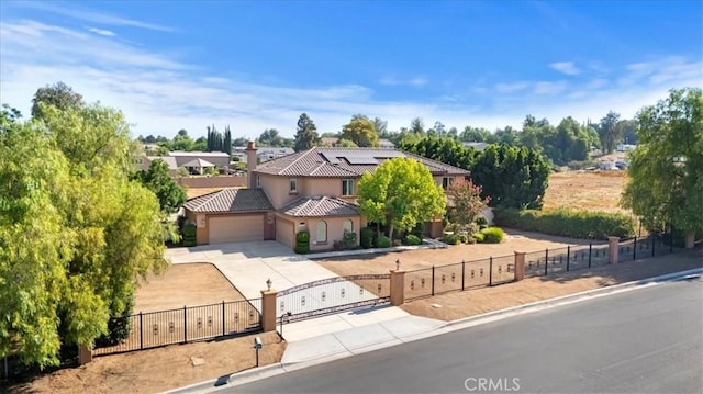 16858 Mariposa Ave, Riverside, CA 92504 - mediterranean / spanish-style home featuring a fenced front yard, a tiled roof, a garage, concrete driveway, and solar panels