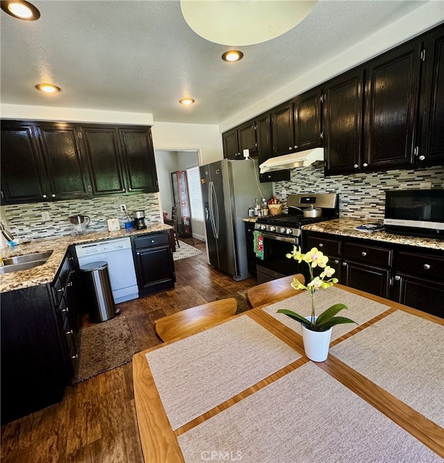 6159 Fleetwood Ln, Chino Hills, CA 91709 - kitchen with appliances with stainless steel finishes, dark cabinets, under cabinet range hood, backsplash, and dark wood-style flooring