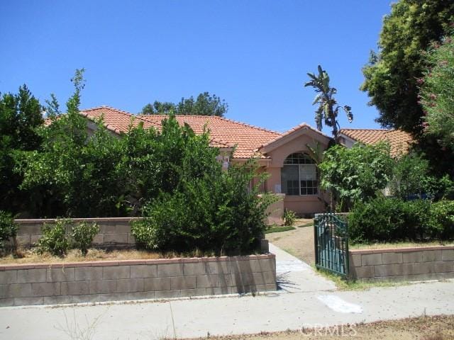 6243 Fallbrook Ave, Woodland Hills, CA 91367 - view of property hidden behind natural elements with a tiled roof, stucco siding, and a gate