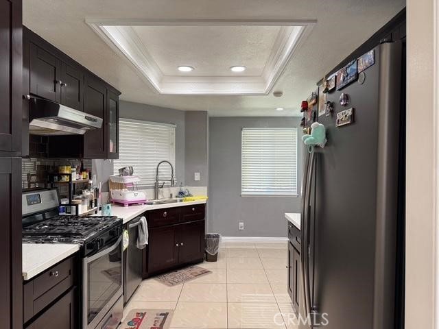 3629 Puente Ave, Baldwin Park, CA 91706 - kitchen featuring stainless steel appliances, under cabinet range hood, a raised ceiling, light countertops, and crown molding