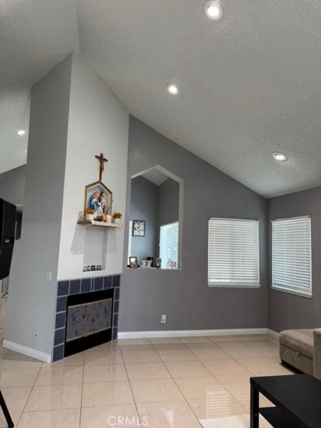 3629 Puente Ave, Baldwin Park, CA 91706 - tiled living area featuring vaulted ceiling, a textured ceiling, a tile fireplace, and recessed lighting