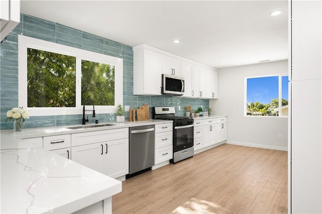 1604 W 125th St, Los Angeles, CA 90047 - kitchen with appliances with stainless steel finishes, light stone countertops, light wood-type flooring, white cabinetry, and recessed lighting