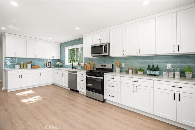 1604 W 125th St, Los Angeles, CA 90047 - kitchen featuring stainless steel appliances, backsplash, light countertops, white cabinets, and recessed lighting