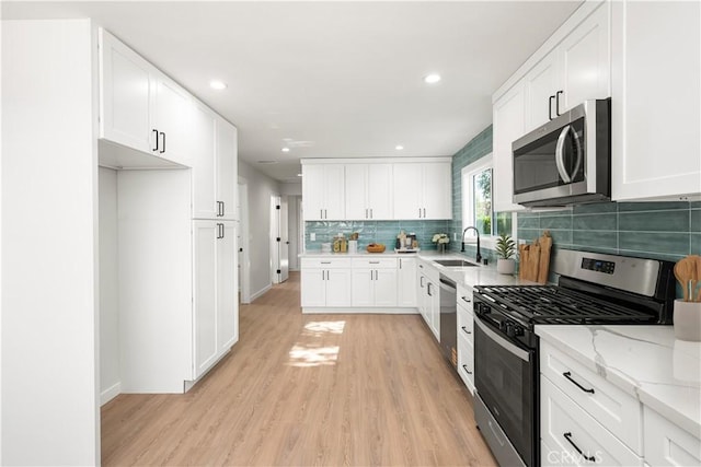 1604 W 125th St, Los Angeles, CA 90047 - kitchen with stainless steel appliances, light wood-style floors, backsplash, white cabinetry, and recessed lighting