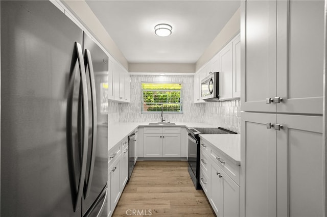 1575 Via Capri Unit 6, Laguna Beach, CA 92651 - kitchen featuring stainless steel appliances, light countertops, tasteful backsplash, light wood-style floors, and white cabinetry