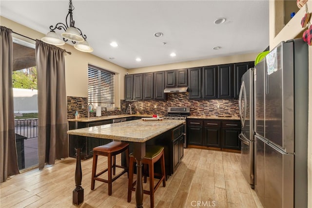 7459 Melanie Ct, Highland, CA 92346 - kitchen featuring under cabinet range hood, light wood-style floors, gas stove, a center island, and recessed lighting