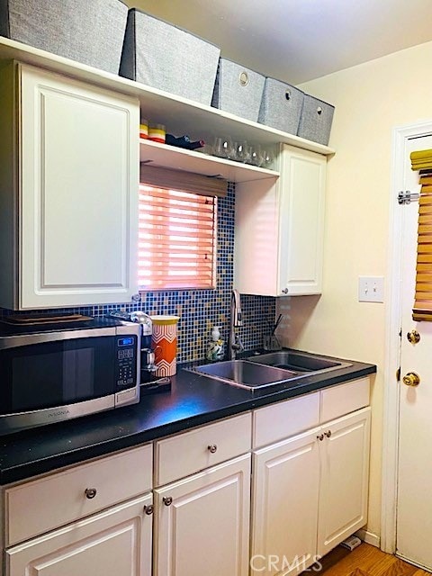 583 S Calle, Abronia, Palm Springs, CA 92264 - kitchen featuring stainless steel microwave, dark countertops, decorative backsplash, and white cabinetry