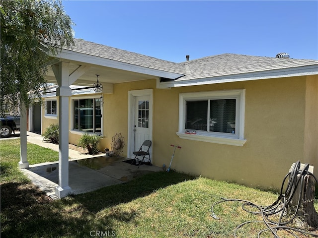 23610 David Ln, Moreno Valley, CA 92557 - view of exterior entry with stucco siding, a lawn, roof with shingles, and a patio area