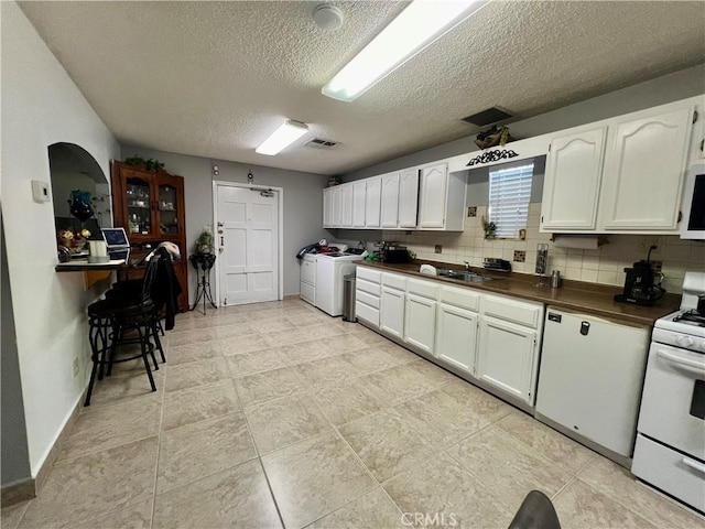 729 W Holt Blvd, Ontario, CA 91762 - kitchen featuring washing machine and clothes dryer, white appliances, dark countertops, a textured ceiling, and white cabinets