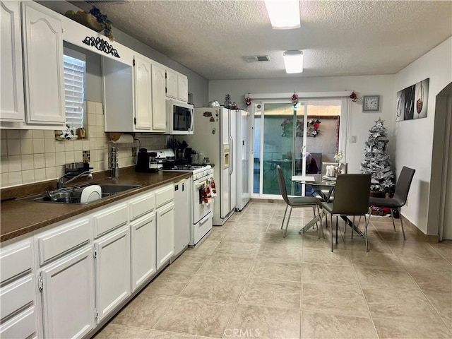 729 W Holt Blvd, Ontario, CA 91762 - kitchen featuring white appliances, dark countertops, a textured ceiling, white cabinets, and backsplash