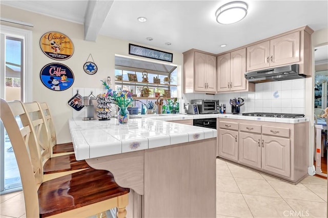 1010 W Yorktown Ave, Montebello, CA 90640 - kitchen featuring tile countertops, under cabinet range hood, a kitchen breakfast bar, healthy amount of natural light, and beam ceiling