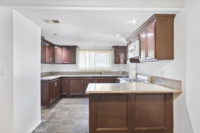 5956 Marlatt St, Jurupa Valley, CA 91752 - kitchen with white microwave, stove, stone finish flooring, a peninsula, and recessed lighting
