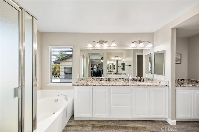 33883 Vinca Ln, Murrieta, CA 92563 - bathroom with a garden tub, double vanity, wood finished floors, a shower stall, and ceiling fan