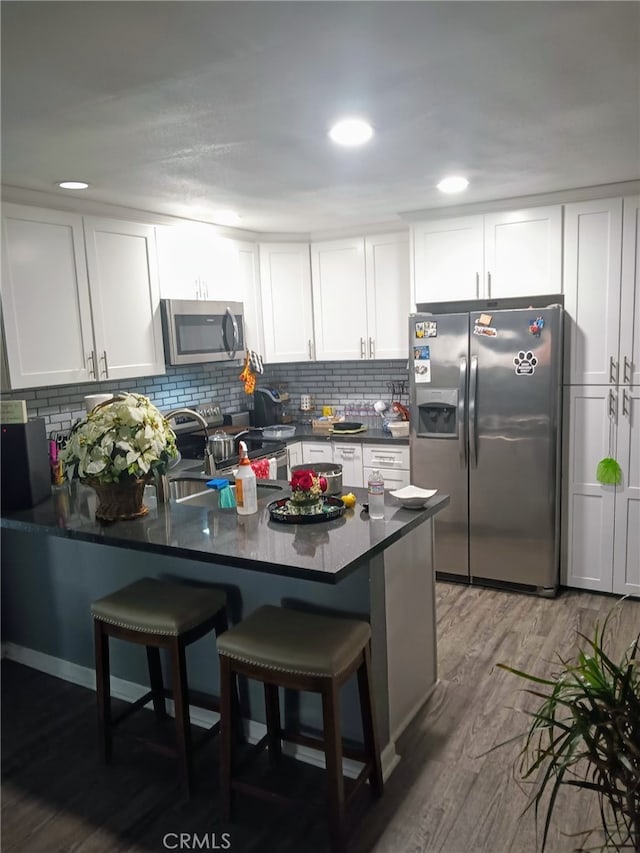 23611 Golden Springs Dr Unit I3, Diamond Bar, CA 91765 - kitchen with stainless steel appliances, a peninsula, dark countertops, white cabinets, and tasteful backsplash