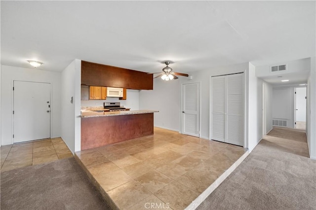 2501 S El Camino Real, San Clemente, CA 92672 - kitchen featuring white microwave, stainless steel electric range, a peninsula, a ceiling fan, and open floor plan