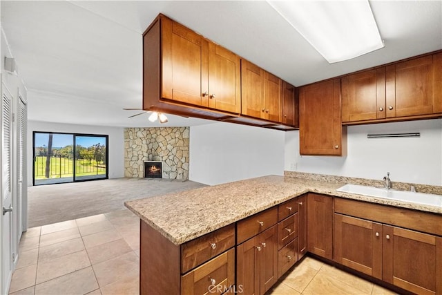 2501 S El Camino Real, San Clemente, CA 92672 - kitchen with light tile patterned floors, a peninsula, light colored carpet, brown cabinets, and a stone fireplace