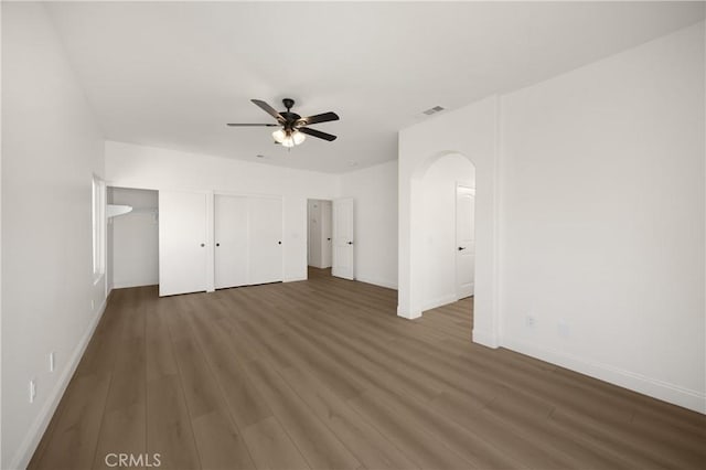 4082 N Flame Tree Ave, Rialto, CA 92377 - unfurnished bedroom featuring wood finished floors, multiple closets, arched walkways, and ceiling fan