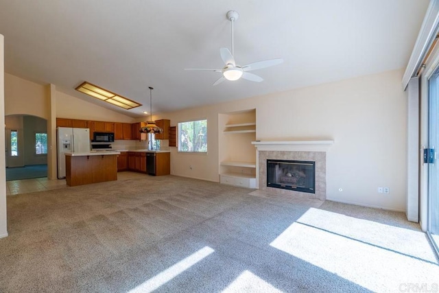 426 Debra An Dr, Fallbrook, CA 92028 - unfurnished living room with light carpet, a ceiling fan, a tile fireplace, vaulted ceiling, and arched walkways
