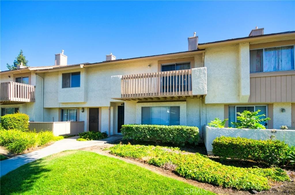 11360 166th St Unit 10, Cerritos, CA 90703 - view of front facade featuring stucco siding, a balcony, a chimney, and a front yard