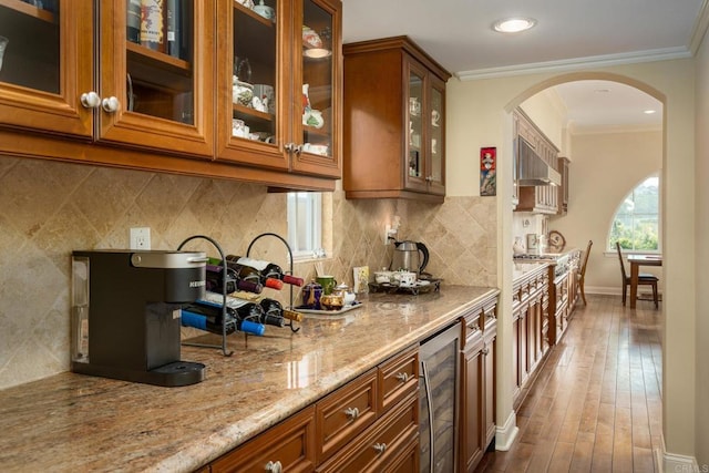 6767 Malachite Pl, Carlsbad, CA 92009 - kitchen with beverage cooler, brown cabinets, light stone countertops, arched walkways, and extractor fan
