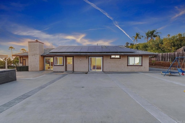 929 Chumash Trl, Vista, CA 92084 - back of house at dusk featuring stucco siding, solar panels, a patio area, and a chimney