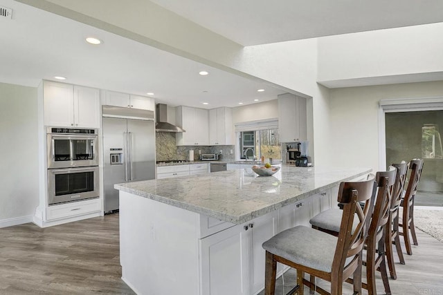 929 Chumash Trl, Vista, CA 92084 - kitchen with stainless steel appliances, wall chimney range hood, light stone counters, tasteful backsplash, and a peninsula