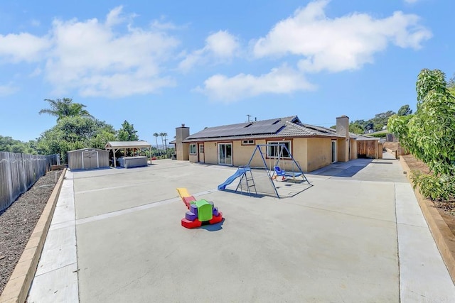929 Chumash Trl, Vista, CA 92084 - back of house with a shed, solar panels, a fenced backyard, a playground, and a chimney