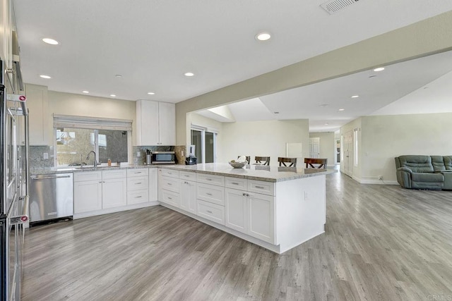 929 Chumash Trl, Vista, CA 92084 - kitchen featuring appliances with stainless steel finishes, open floor plan, light wood-type flooring, light stone counters, and white cabinets