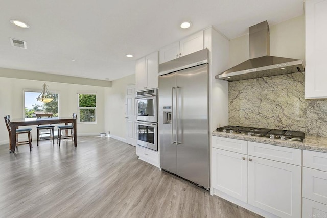 929 Chumash Trl, Vista, CA 92084 - kitchen with wall chimney exhaust hood, stainless steel appliances, light wood-type flooring, tasteful backsplash, and white cabinetry
