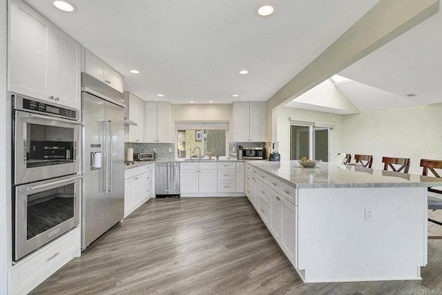 929 Chumash Trl, Vista, CA 92084 - kitchen featuring appliances with stainless steel finishes, a breakfast bar area, a peninsula, white cabinetry, and recessed lighting