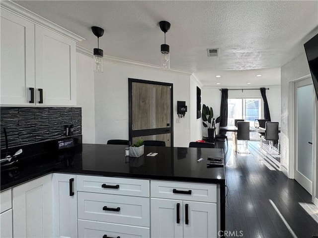 9135 Cord Ave, Downey, CA 90240 - kitchen with a peninsula, decorative backsplash, white cabinets, dark countertops, and ornamental molding