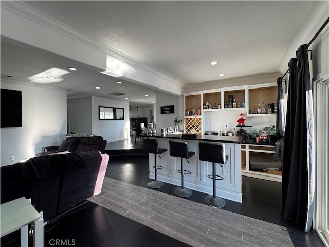 9135 Cord Ave, Downey, CA 90240 - kitchen featuring dark countertops, a kitchen breakfast bar, ornamental molding, dark wood finished floors, and recessed lighting